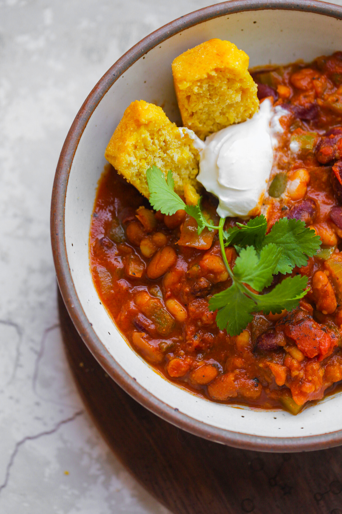 veggie chili with cornbread and sour cream in a bowl