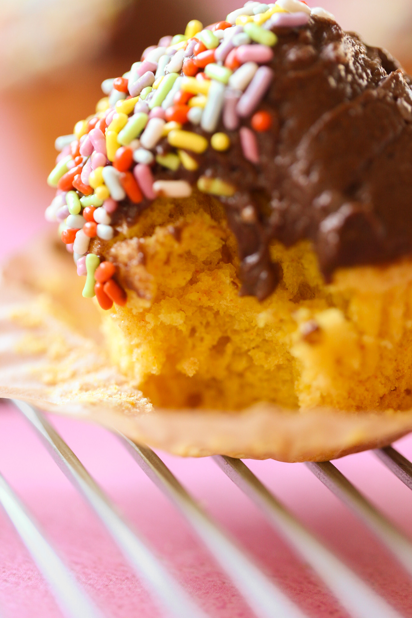 yellow cake cupcake with chocolate and sprinkles and a bite