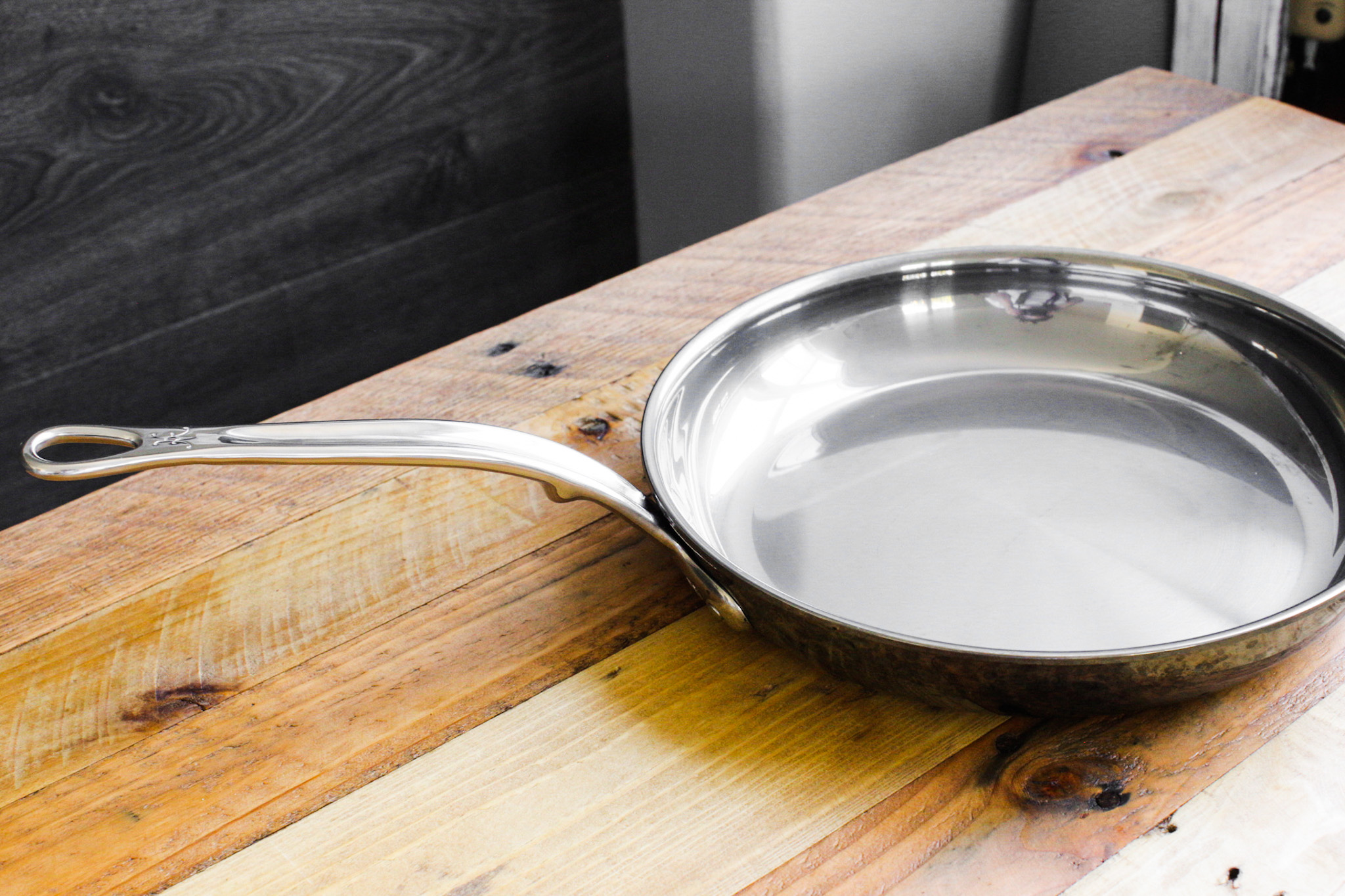 shiny hestan skillet on wood table