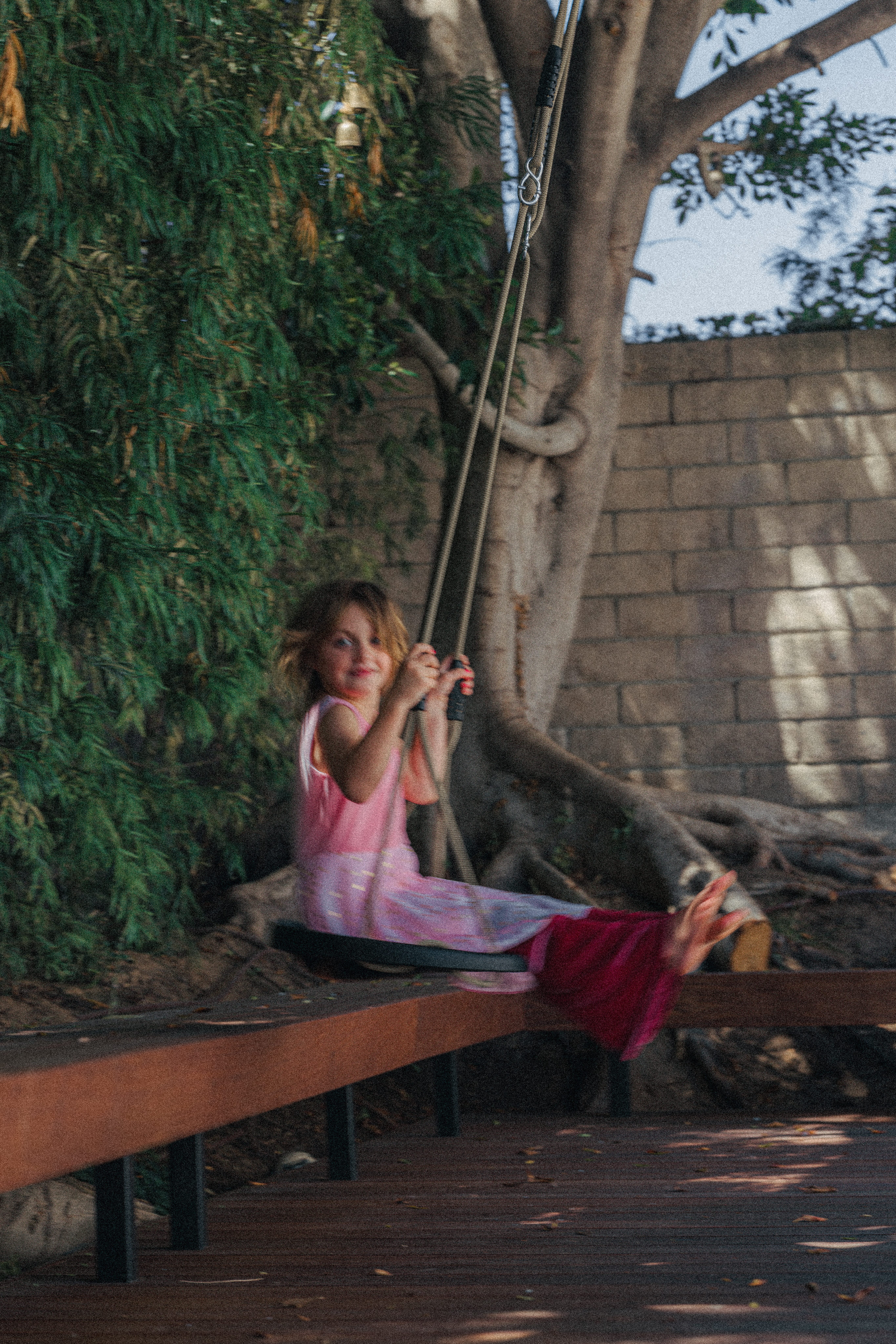 girl swinging under tree